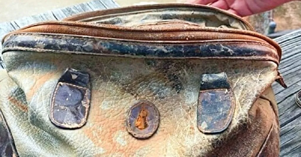Un garçon sort un vieux sac à main de l’eau et agit rapidement après avoir jeté un coup d’œil à l’intérieur